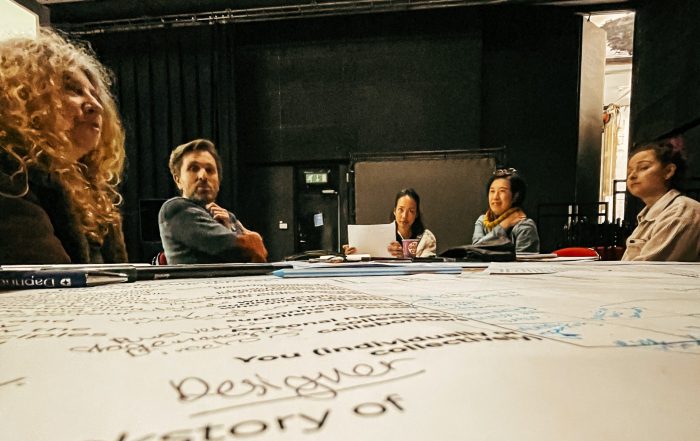 Group of people sat around a table looking at The Ecostage Framework Worksheets